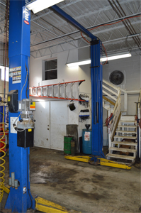 Garage of Lyco Lube XXpress with white steps leading to an office and a hanging red ladder over large white doors next to electric jacks in Williamsport, PA.